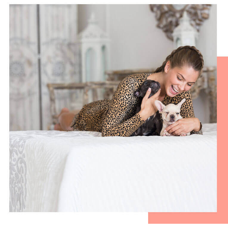 a woman sleeping on a bed holding a frenchhbulldog puppy